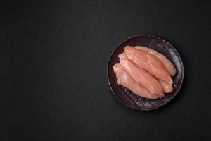 Raw chicken fillet cut into strips with spices and herbs photo