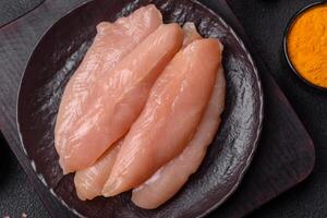 Raw chicken fillet cut into strips with spices and herbs photo