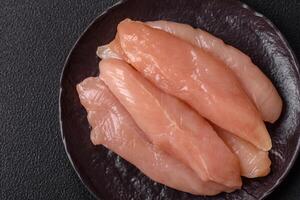 Raw chicken fillet cut into strips with spices and herbs photo