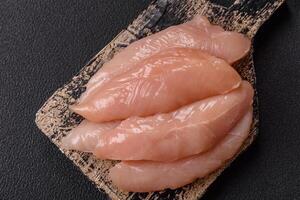 Raw chicken fillet cut into strips with spices and herbs photo