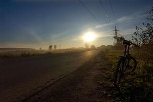 Sunset in background of the road and fields with grass and trees. photo
