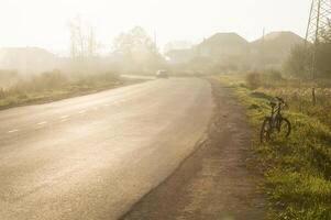 Sunset in background of the road and fields with grass and trees. photo