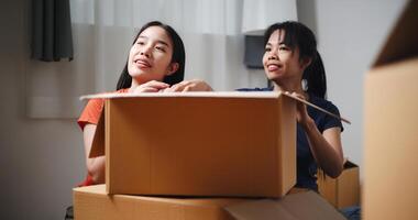 Portrait of Two siblings happily sit on the floor talking as they unpack belongings from boxes to decorate a room in new home. Moving to a new home concept photo