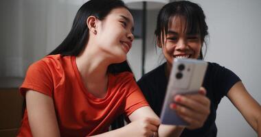 Portrait of Two siblings happily chatting on the floor and using mobile phone to check if the items in the boxes they moved from old house are complete. Moving to a new home concept photo