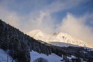 Clouds are moving around a mountain peak in the Swiss Alps, Grisons, Switzerland photo