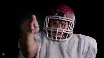 American football player in team uniform, pads, and helmet, confidently pointing at the camera. A powerful, action-packed image capturing team spirit and readiness for the game video