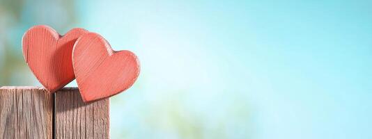 Two wooden hearts on a rustic surface against a soft blue background. photo