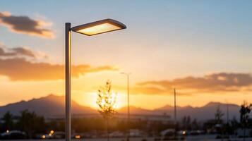 A street lamp illuminated against a sunset backdrop with mountains. photo