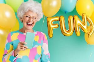 Happy elderly woman joyfully laughing during a call with colorful decorations spelling fun in the background, showcasing connection and celebration photo