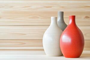 Ceramic vases in red, violet-gray, and beige arranged on a wooden surface with soft shadows and muted lighting for a modern decorative display photo