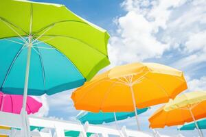 Vibrant summer beach party setup with colorful umbrellas and chairs under a sunny sky for fun and relaxation photo