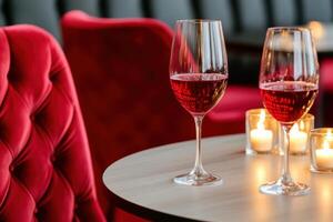 Elegant burgundy velvet chairs surround a table with candles and wine glasses, creating a cozy atmosphere for an intimate gathering photo