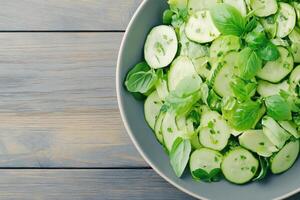 Fresh garden salad with avocado slices and herbs served in a gray ceramic bowl on a wooden table photo
