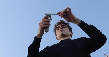 Barber holds in his hands a clipper and a comb video