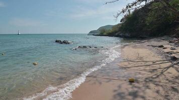 A beach with a boat in the water and a few rocks video