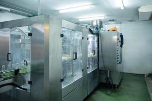 Beverage bottling room with automatic machinery and control panel in production line at processing factory photo