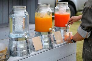 Hands holding a glass is filling juice from tank photo
