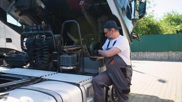 Senior truck mechanic engineer inspects transport cargo uses laptop to search for errors and breakdowns and writes data to the computer video