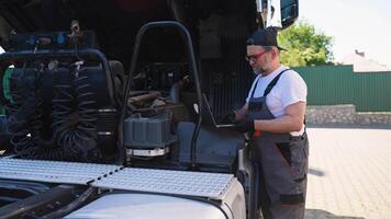 Vehicle mechanic with diagnostic tool laptop working near truck in workshop video