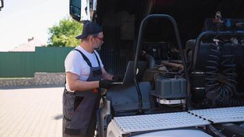 Senior mechanic using laptop while working at truck repair workshop video