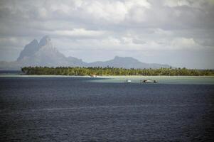 A boat is out on the water with a mountain in the background photo
