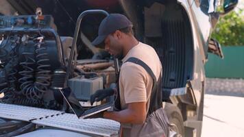 African American mechanic using laptop while working at truck repair workshop video