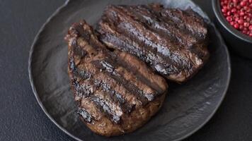Grilled beef steak with salt, spices and herbs on dark concrete background video