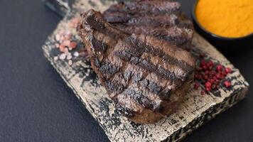 Grilled beef steak with salt, spices and herbs on dark concrete background video