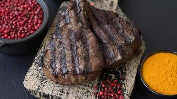 Grilled beef steak with salt, spices and herbs on dark concrete background video