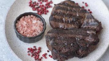 Grilled beef steak with salt, spices and herbs on dark concrete background video