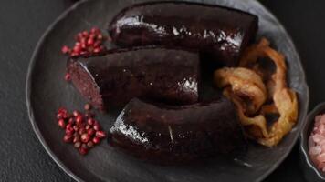 Delicious black blood sausage or black pudding with spices and herbs grilled on a black concrete background video
