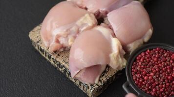 Fresh raw chicken thigh fillets with salt, spices and herbs on a dark concrete background video