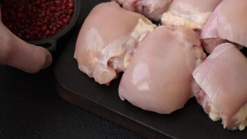 Fresh raw chicken thigh fillets with salt, spices and herbs on a dark concrete background video