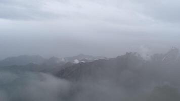 Panoramic view of snow capped mountains against cloudy gray sky, Kazakhstan. Gloomy sky video