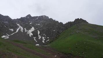 Into the mountains from Shymbulak, near Almaty, Kazakhstan. Capped mountain range against cloudy sky video