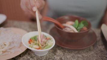 Close-up of a woman hand using chopsticks to pick up noodles from a bowl of soup. video