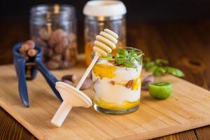 homemade yogurt with kiwi, honey and nuts in a glass on a wooden table photo