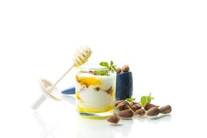 homemade yogurt with kiwi, honey and nuts in a glass, isolated on white background photo
