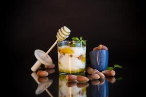 homemade yogurt with kiwi, honey and nuts in a glass, isolated on black background photo