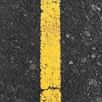 Close-up of a yellow road line on asphalt background photo