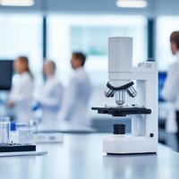 Microscope on lab table with scientists in background. photo