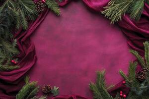 Christmas background with pine branches, red fabric, and decorations. Christmas frame on a dark pink canvas. photo