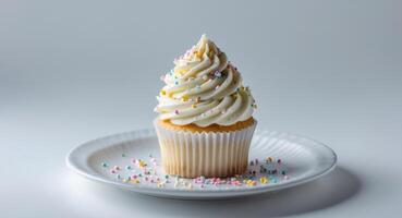 Delightful pastel cupcake with creamy frosting and decorative sprinkles on a white plate photo