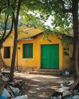 Village House with Yellow Walls and Green Doors Surrounded by Trees and some Garbage photo