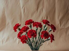 Red carnations bouquet on light brown paper backdrop symbolizing remembrance with space for text ideal for greeting cards and memorial purposes. photo