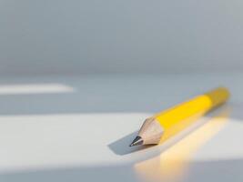 Bright yellow pencil lying on a clean surface with a sharp tip ready for writing or drawing activities. photo