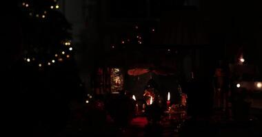 Wooden carousel with candles spins gently among festive decorations, creating a warm and inviting atmosphere during a holiday gathering. Night scene with Christmas lights and soft glow of candles video