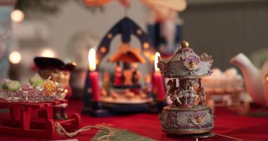 Delicate vintage carousel music box spins gently among charming festive decorations, creating a warm and inviting atmosphere during a holiday gathering. The soft glow of candles enhances the scene. video