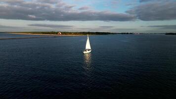 Sailboat Navigating Expansive Waters with Distant Red and White Structure video