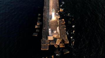 Aerial View of Pier with White Lighthouse Extending into Dark Waters video